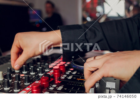 DJ's hand over the laptop and mixing console controlling the sound settings. 74146050