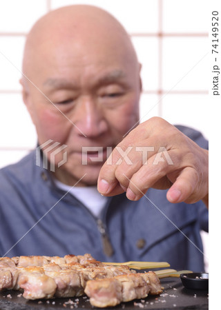焼き鳥に塩をふるシニア男性 焼き鳥に塩をふるシニア男性 74149520