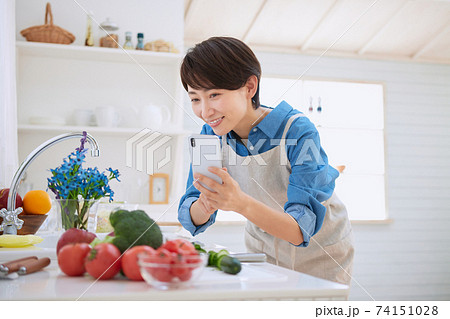 キッチンで写真を撮るミドル女性 74151028