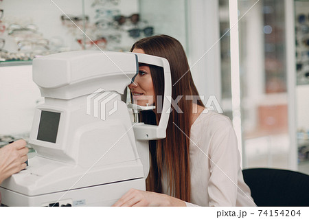 A woman doctor and patient doing opthalmology check vision test by refractometer 74154204