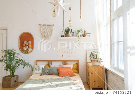 A cozy room in the sunlight. Beautiful bed in a modern interior A cozy room in the sunlight. Beautiful bed in a modern interior 74155221