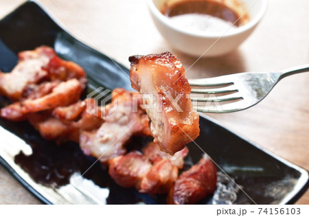 grilled pork neck slice on plate stabbing on silver fork dipping spicy sauce grilled pork neck slice on plate stabbing on silver fork dipping spicy sauce 74156103