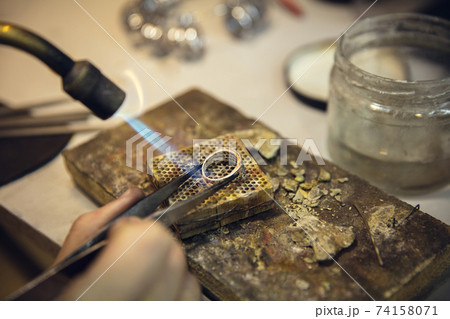 Close up hands of jeweller, goldsmiths making of silver ring with gemstone using professional tools. Close up hands of jeweller, goldsmiths making of silver ring with gemstone using professional tools. 74158071