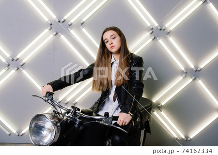 Young fashion girl posing in black leather with motorcycle. 74162334