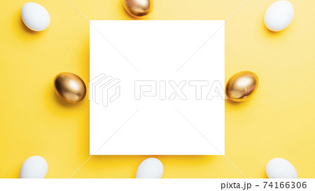 Easter luxury. Golden, white colour egg on pastel yellow background in Happy Easter decoration. Flat lay, top view. 74166306