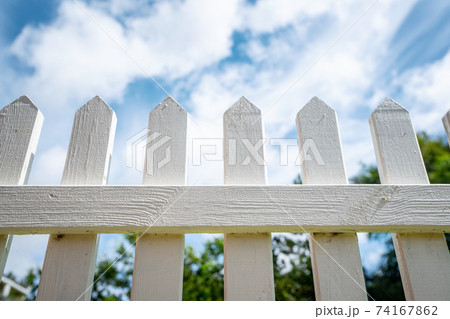 White picket fence under a blue sky White picket fence under a blue sky 74167862