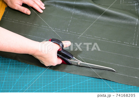 craftsman cuts green leather using scissors craftsman cuts green leather using scissors 74168205