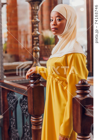 beautiful Muslim girl in hijab smiling, waiting for her food in a restaurant. 74168746