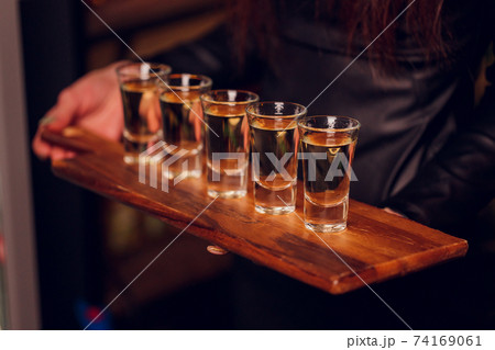 Variation of hard alcoholic shots served on bar counter. Blur bottles on background. 74169061