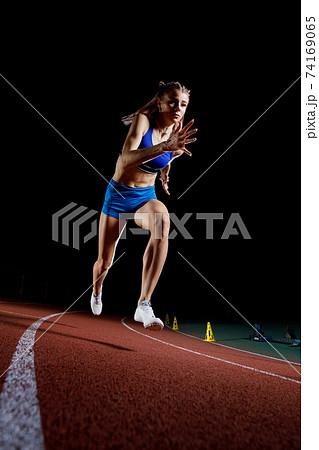 Female track runner bursting off starting block 74169065