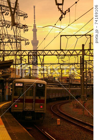 夕焼けに染まるスカイツリーとステンレス車の通勤電車・10000系 74169106