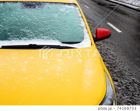 frozen windshield of yellow car parked on road 74169733