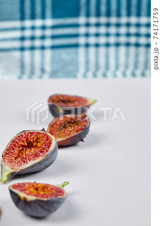 Fig slices on a white background with a blue tablecloth Fig slices on a white background with a blue tablecloth 74171759