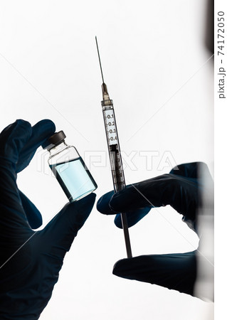 Doctor or Nurse Wearing Surgical Gloves Holding Vaccine Vial and Medical Syringe Doctor or Nurse Wearing Surgical Gloves Holding Vaccine Vial and Medical Syringe 74172050