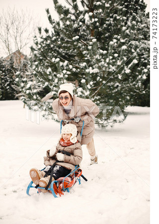 Mother and child in winter clothes play at the yard 74173223