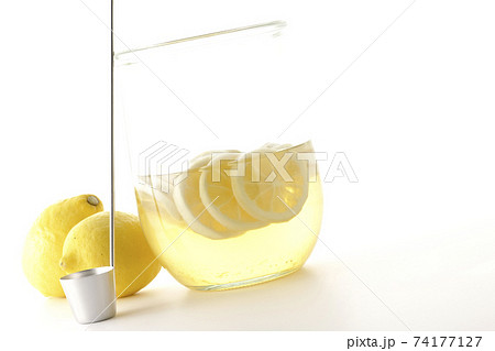 保存瓶に入ったレモンスカッシュやレモネードの原液とレードルとレモンを白背景で撮影 74177127