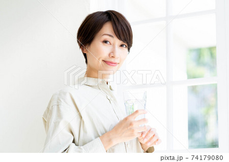 窓際で水を飲む女性 74179080