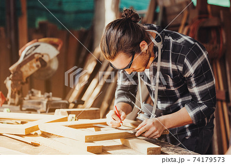 Confident wood worker expert. Young man working at factory. Skilled carpenter 74179573