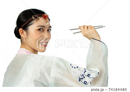 Young beautiful woman holding asian chopsticks with big smile. Beautiful young woman with perfect smile tooth. Isolated on white. asian girl dressing in traditional Hanbok style portrait Young beautiful woman holding asian chopsticks with big smile. Beautiful young woman with perfect smile tooth. Isolated on white. asian girl dressing in traditional Hanbok style portrait 74184480