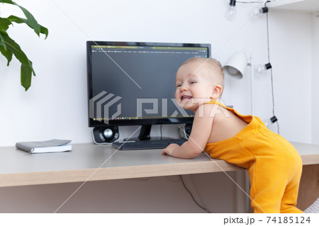 Caucasian funny little baby boy exploring computer, monitor and keyboard 74185124