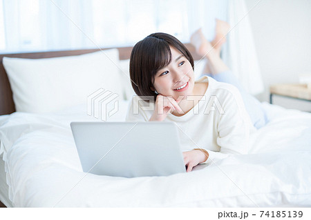 女性 うつ伏せ パソコン 寝室の写真素材
