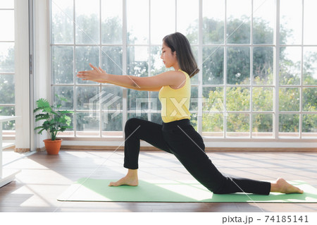 Asian young beautiful woman practicing Yoga and exercising on mat in living room at home 74185141