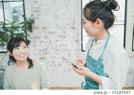 スマホでオーダーをとる飲食店女性スタッフ スマホでオーダーをとる飲食店女性スタッフ 74185645