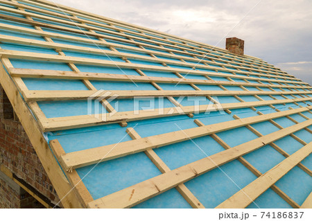 Brick house with wooden roof frame under construction. Brick house with wooden roof frame under construction. 74186837