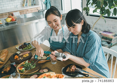 デジカメで食卓の料理写真を撮る女性の写真素材