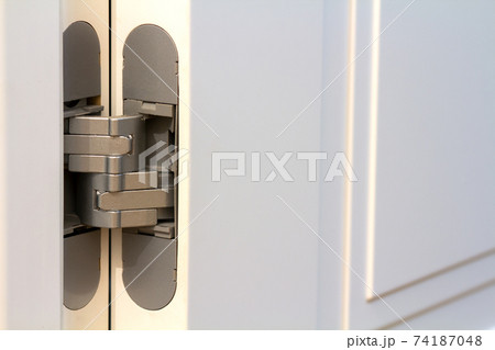 New modern metal door hinges on white wooden doors. New modern metal door hinges on white wooden doors. 74187048