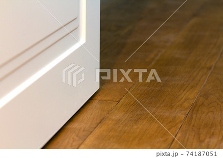Detail of contemporary white room door on wooden yellow floor. 74187051