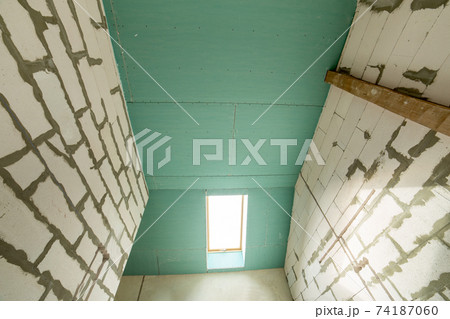 Interior of an apartment room with bare walls and ceiling under construction. 74187060