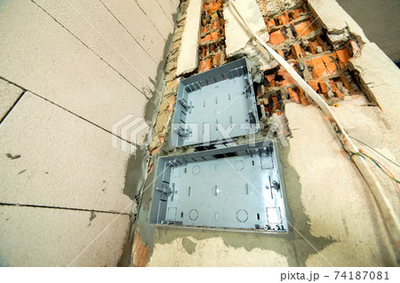 Electrical cables laid to plastic fusebox installed on the wall in a room under construction works. 74187081