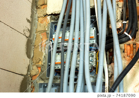 Electrical cables laid in protective corrugation installed on the ceiling and wall in a room under construction works. Electrical cables laid in protective corrugation installed on the ceiling and wall in a room under construction works. 74187090