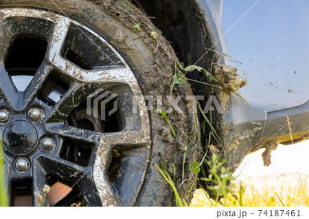 Close up of dirty off road car wheels with dirty tires covered with yellow mud. 74187461