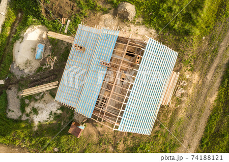 Aerial view of a brick house with wooden roof frame under construction. Aerial view of a brick house with wooden roof frame under construction. 74188121