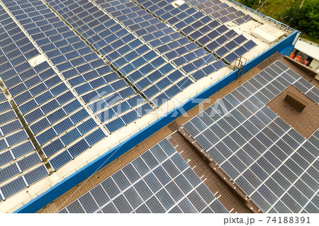 Aerial view of solar power plant with blue photovoltaic panels mounted of industrial building roof. 74188391