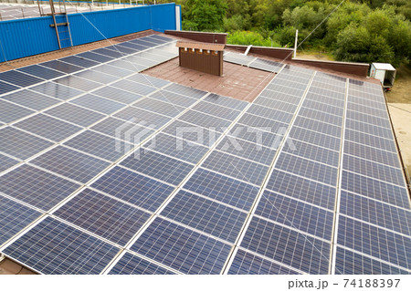 Aerial view of solar power plant with blue photovoltaic panels mounted of industrial building roof. 74188397