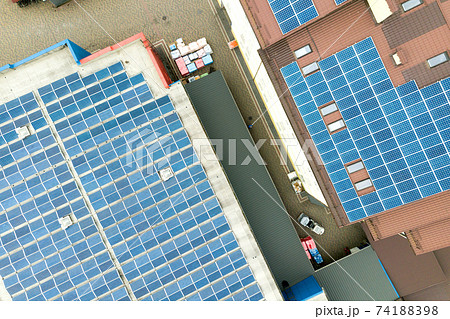 Aerial view of solar power plant with blue photovoltaic panels mounted of industrial building roof. 74188398
