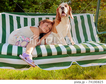 Happy little girl playing with dog in garden. Happy little girl playing with dog in garden. 74190825