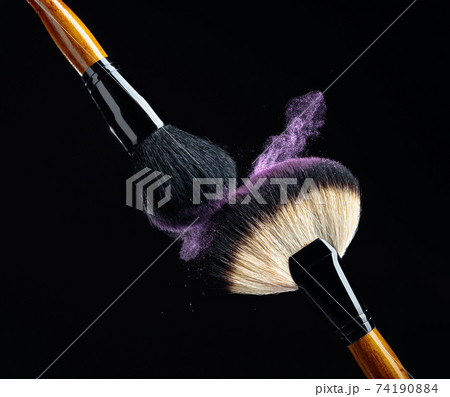 Makeup concept with a  professional makeup brushes with glowing purple eye shadow. 74190884