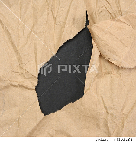 brown sheet of paper with a torn hole and a curled strip 74193232
