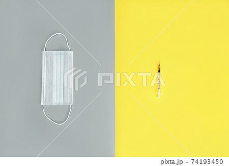 Syringe and medical mask on trendy yellow and grey background. Medicine background. Coronavirus vaccine concept. 74193450