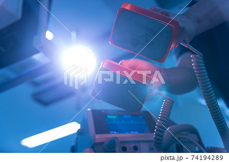 The doctor is giving a defibrillators to save the patient's life in the hospital. CPR The doctor is giving a defibrillators to save the patient's life in the hospital. CPR 74194289