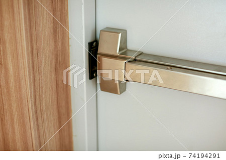 Emergency fire exit door. Closed up latch and rusty door handle of emergency exit. Emergency fire exit door. Closed up latch and rusty door handle of emergency exit. 74194291
