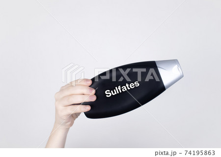 Chemical components on the shampoo label: Sulfates. Female hands hold the jar on which indicates the harmful ingredient. White background, place for your text Chemical components on the shampoo label: Sulfates. Female hands hold the jar on which indicates the harmful ingredient. White background, place for your text 74195863