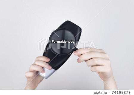 Chemical components on the shampoo label: Formaldehyde. Female hands hold a magnifying glass on the jar, which indicates the harmful ingredient. White background, place for your text 74195873
