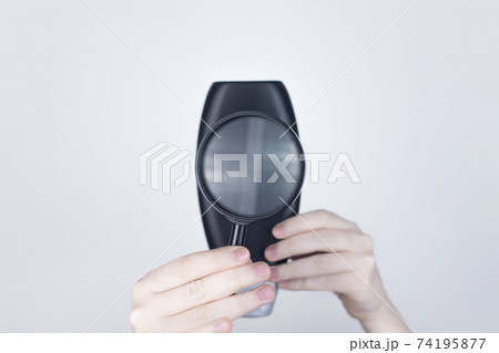 Chemical or natural components of the shampoo, ingredients and composition of the hair product. Female hands hold a black shampoo jar and a magnifying glass. Place for text 74195877