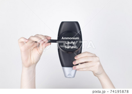 Chemical components on the shampoo label: Ammonium Lauryl Sulfate. Female hands hold a magnifying glass on the jar, which indicates the harmful ingredient. White background, place for your text Chemical components on the shampoo label: Ammonium Lauryl Sulfate. Female hands hold a magnifying glass on the jar, which indicates the harmful ingredient. White background, place for your text 74195878