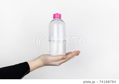 A woman is holding an micellar water. Place for your text. The concept of hazardous substances in cosmetics and household chemicals 74198764